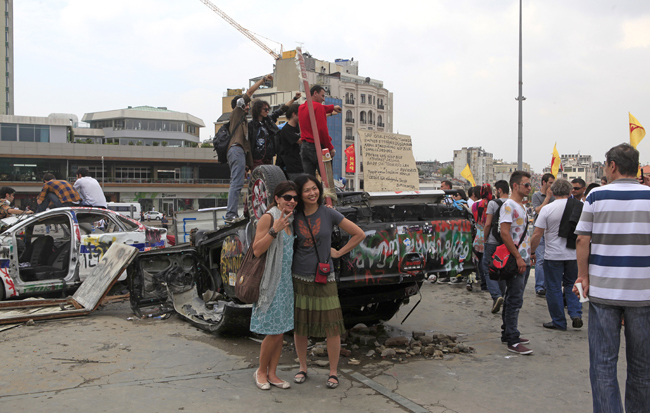 Touristinnen vor zerstörten Autos am Taksim-Platz